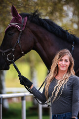Obraz premium Young woman with long hair and blonde streaks, stands portraits with her horse.