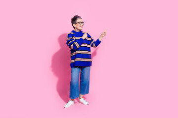 Full body photo of attractive pensioner woman point look empty space dressed stylish blue striped clothes isolated on pink color background