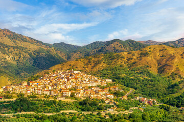 Fototapeta na wymiar amazing mountain landscape with old yellow italian town among green beatiful mountains and cloudy sky above