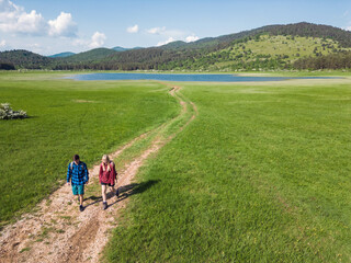 Two young adults, male and female, with backpacks, enjoying time together during a hike on a beautiful sunny spring day.