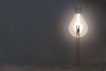 surreal man climbs a ladder to reach an illuminated light bulb, new ideas symbol concept - 752850223
