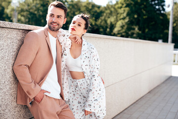 Naklejka premium Beautiful fashion woman and her handsome elegant boyfriend in beige suit. Sexy brunette model in summer clothes. Fashionable smiling couple posing in street Europe. Brutal man and female outdoors