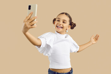 Smiling teen girl child isolated on nude brown studio background talk on video call on cellphone....
