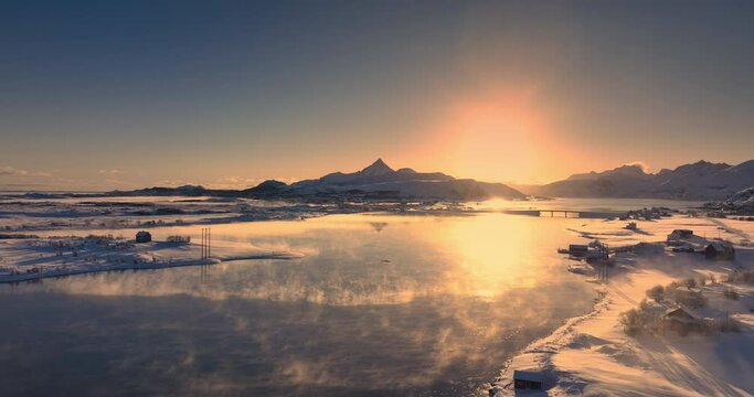 Aerial sunset view of winter landscape of frozen rocky sea beaches of Lofoten islands coastline with norwegian snowy mountains hills, Norway