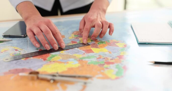 Woman measures distance between points on map with ruler