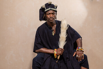 traditional african man in ceremonial attire holding cultural artifacts