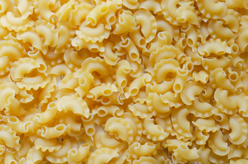 Background of Creste Di Gallo raw pasta sprinkled. Rooster comb. The concept of traditional Italian food. Horizontal orientation. Copy space. Selective focus. Top view