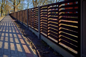 Long wooden fence. Fencing of private territory. Fence along the sidewalk.