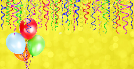 Yellow blurred background with balloons and different colored confetti and streamers for party...