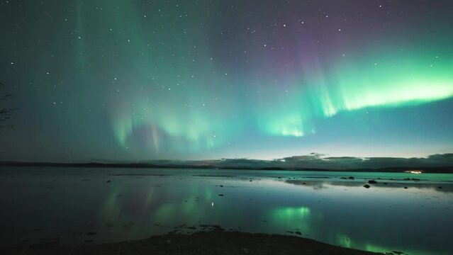 A magnificent dance of Aurora Borealis above the mirrorlike fjord. A timelapse video.