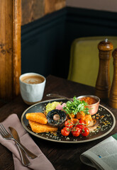 English Breakfast served on a black ceramic plate. Wooden table. Top view