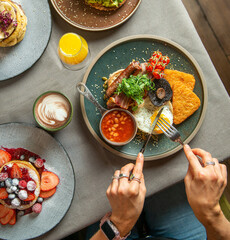 English breakfast  for breakfast or lunch time on a plate with cutlery on woman's hands. 