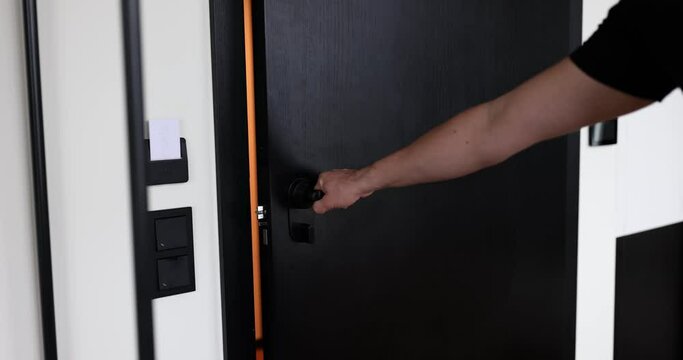 Man closes apartment door standing in light corridor