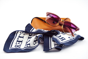 fashionable women's sunglasses. A case for storing glasses. they are lying on a woman's scarf....