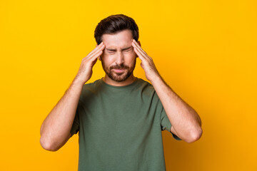 Photo of tired exhausted man wear khaki t-shirt feeling headache arms temples isolated yellow color...