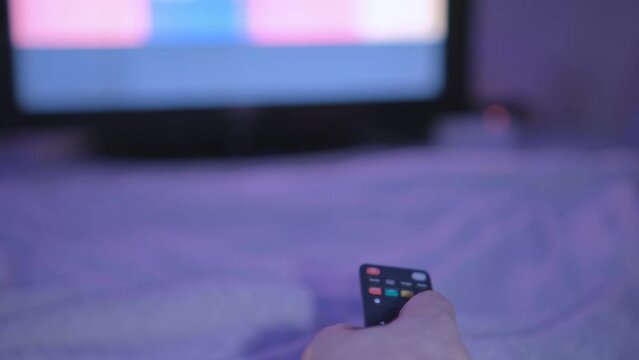 4K men hand holding the TV remote control and turn off smart tv. Channel surfing, focused on the hand and remote control. Internet TV at living room on holiday on sofa