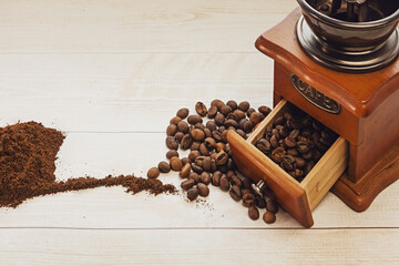 Hand coffee grinder, ground coffee and coffee beans on a wooden background. Copy space