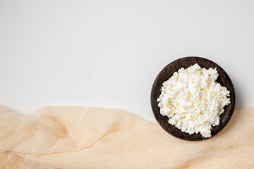 Close-up of fresh cottage cheese on a wooden plate isolated on a white background. Healthy vegetarian breakfast. Top view, copy space.