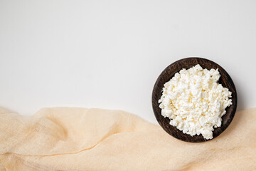 Close-up of fresh cottage cheese on a wooden plate isolated on a white background. Healthy...