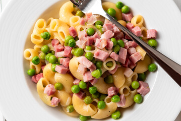 Piatto di maccheroni con prosciutto e pisellini, cibo italiano 