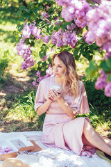 Serene Moment Under Lavender Lilac Blooms in Springtime. woman relaxes with a cup under blooming lilac bushes, enjoying a peaceful spring day.