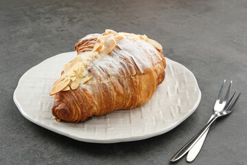 Almond Croissant with sprinkling icing sugar on white plate 
