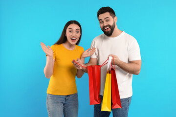 Obraz premium Excited couple with shopping bags on light blue background