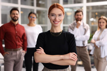 Portrait of happy businesswoman and her team in office