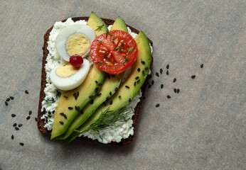 Healthy toast with cottage cheese, avocado, egg and tomato. A rustic sandwich.