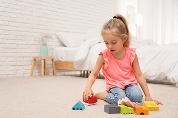 Cute child playing with building blocks on floor at home