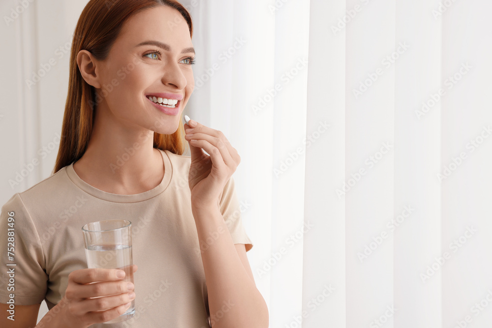 Sticker beautiful young woman taking vitamin pill at home. space for text