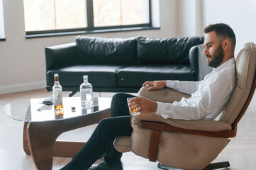 Life crisis. With whiskey. Upset young man drinker alcoholic is indoors