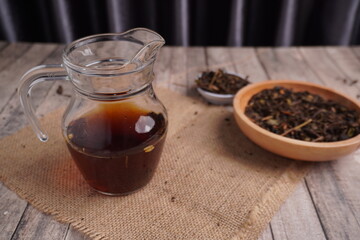 black tea in clear jar and dried tea leaves on side as ornament