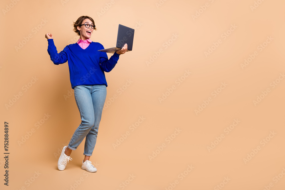 Poster full size photo of attractive delighted girl use netbook raise fist shout yes empty space isolated o