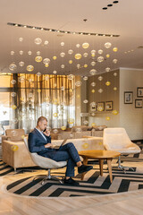 Successful business man in a stylish suit works on a laptop, concentrating on online communication...