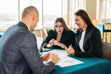 A group of people in a modern coworking space discuss the tasks and business processes of the team. Collection of managers or analytics. Growth analysis, chart, statistics and data. People work in a b