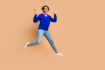 Full length photo of impressed energetic person jump raise hands empty space isolated on beige...