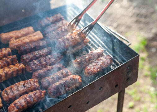 small Romanian minced meatrolls called mici or mititei, similar to serbian cevapi, fresh balkan skinless sausages, cooked outside on the barbecue