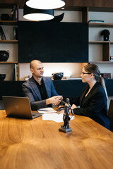 A lawyer meets with a new client. A young male lawyer in a suit sits at an office desk, shares...