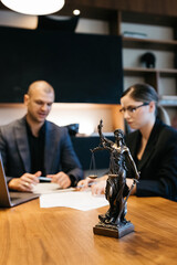 A lawyer meets with a new client. A young male lawyer in a suit sits at an office desk, shares...