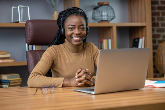 Adult woman with dreadlocks in headphones offers online tutorials using laptop