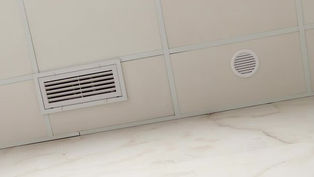 Ventilation grilles are mounted in the suspended ceiling. Ventilation and air conditioning system in the bathroom. View from below, in rotating motion.