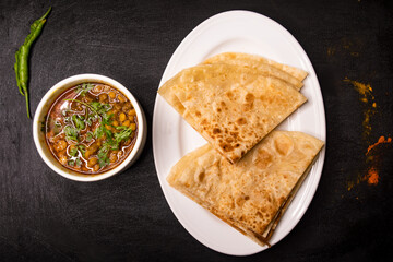 paratha with dal chana or chanay served in dish isolated on dark background top view indian spices,...
