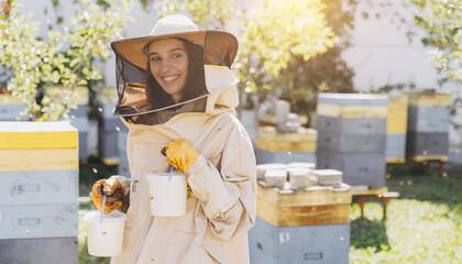 Happy smiling female beekeeper holding ready organic honey made in bee farm