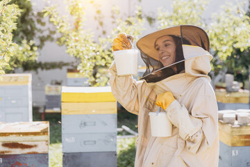 Happy smiling female beekeeper holding ready organic honey made in bee farm