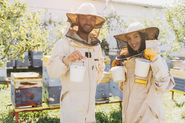Happy smiling international couple of beekeepers holds ready organic honey made on a bee farm