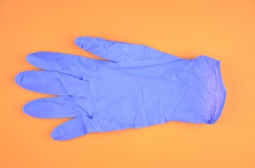 Blue latex medic (medical) glove on an orange background