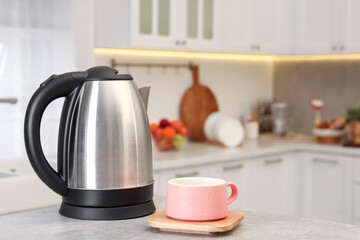 Electric kettle and cup on table in kitchen. Space for text