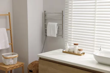  Heated rail with towel on white wall in bathroom © New Africa