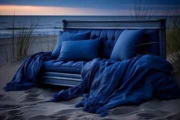 Elegant blue sofa on the tranquil beach at sunset, offering a serene spot to relax and enjoy the view of the calm sea and golden sand, perfect for contemplation and appreciation of natures beauty.
